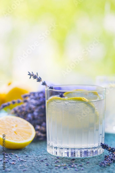 Fototapeta Lemonade with lemons and lavender on stone table over nature background