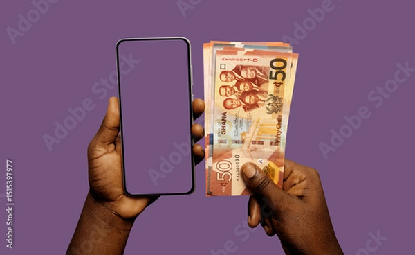 Obraz Black African hand holding mobile smart phone with blank screen and Ghanaian cedi notes in another hand over purple background 
