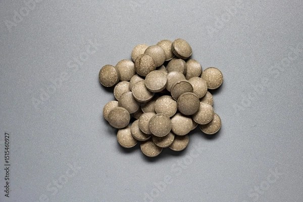 Fototapeta Round green tablets of iron supplements on gray background. Health medication