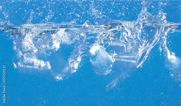Fototapeta Falling ice tube in motion with splashing water, creating air bubbles scatter around, blue background isolated. Ice tube fall into water with air bubbles
