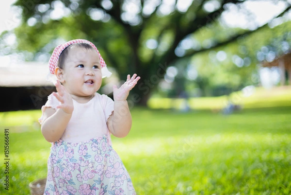 Obraz Happy baby girl enjoys leisure time outdoors during family picnic with people around in natural park concept creating joyful and peaceful atmosphere