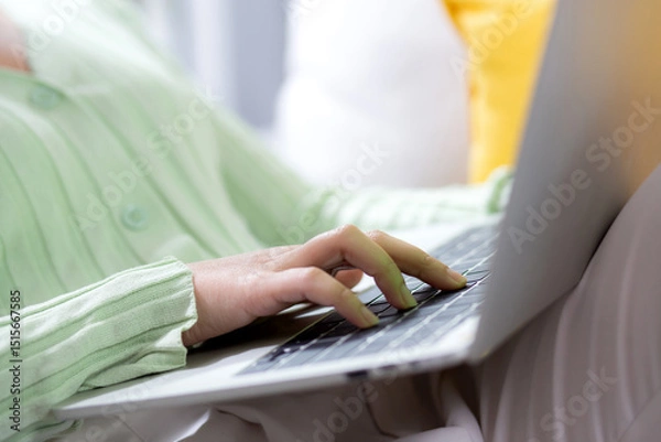 Obraz Closeup hands young woman sitting on sofa using laptop computer working from home in the living room at home, female is freelance using notebook online, one person, business and lifestyles concept.