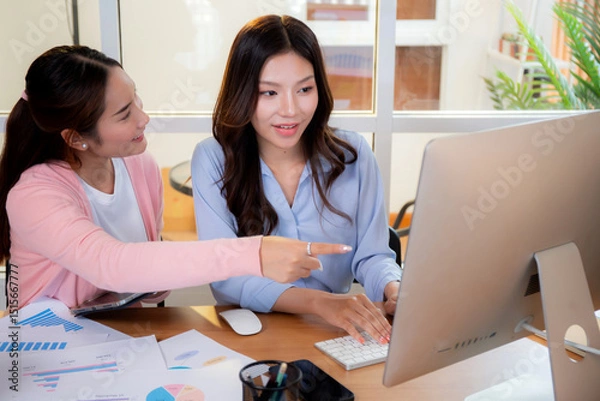 Obraz Two asian businesswoman collaborating on data analysis marketing financial with charts at home office, working together with graphs on computer screen, teamwork and marketing strategy planning.