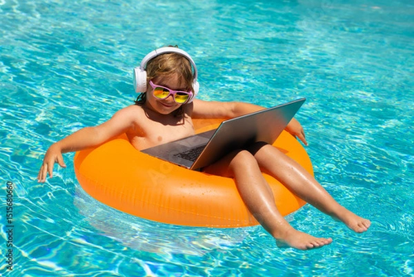 Fototapeta Summer business. Little business man relaxing in the pool with laptop. Kid online working on laptop, swimming in a sunny turquoise water pool.