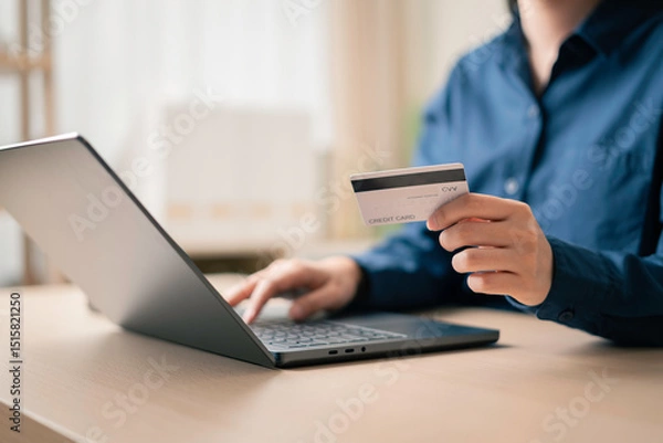 Fototapeta person making an online purchase on a laptop while holding a credit card, showcasing digital banking and convenient e-shopping