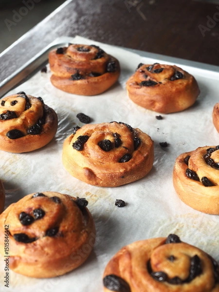 Fototapeta cinnamon and raisin bread rolls on baking tray