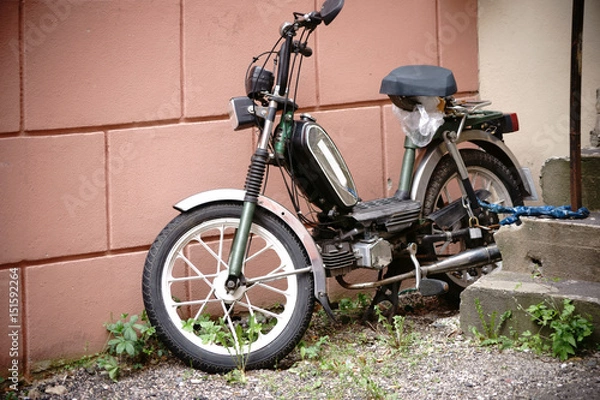 Obraz Motorower Oldtimer / Profil boczny starego Motorowera Oldtimer przymocowanego łańcuchem do filaru schodów.