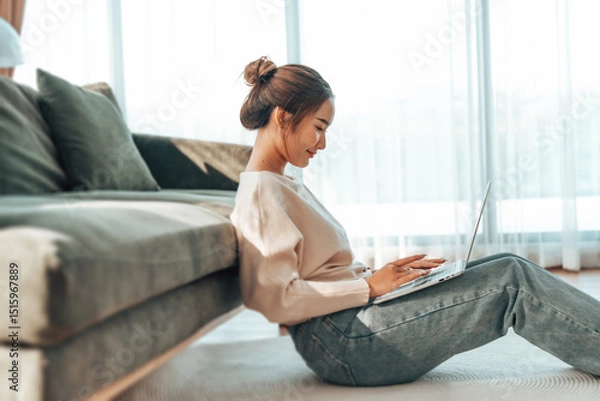 Fototapeta Young Asian beautiful woman relaxing on comfortable couch, using laptop at home, happy girl chatting with friends in social network, spending weekend, watching movie, shopping online
