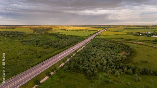 Fototapeta A3 Highway Through Green Fields. An aerial shot captures the A3 highway in Gherghița, Prahova County, Romania, cutting straight through a vibrant landscape of green fields and patches of trees