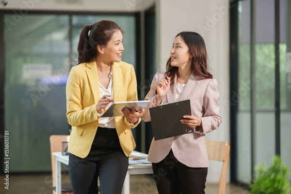 Fototapeta Group of two Asian businesswomen using laptops and tablets having a meeting about working together.
