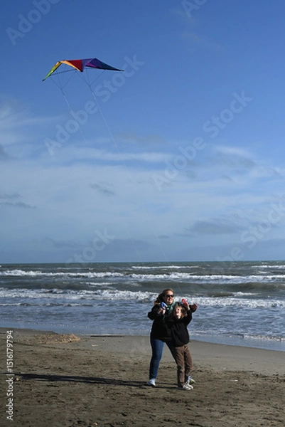 Fototapeta mother and child playing with a kite against a blue sky