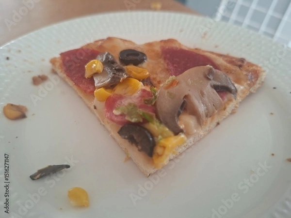 Obraz a closeup shot of a delicious pizza with a slice of tomato and a slice of pizza on a plate