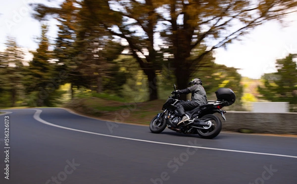 Fototapeta Driver riding motorcycle on empty asphalt road, spring mountains