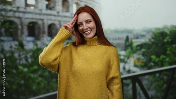 Fototapeta Woman smiling in yellow sweater with red hair standing outside roman coliseum on a sunny day in italy with greenery around creating a vibrant outdoor atmosphere.