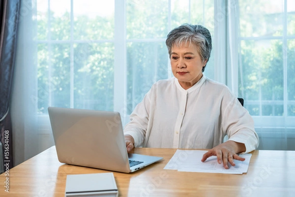 Fototapeta Senior Asian businesswoman manager working on laptop at office desk with documents in professional environment