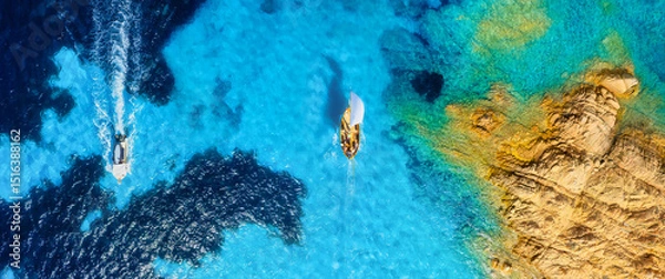 Fototapeta Sailing yacht at sea. Summertime vacation. Drone view on the yacht and motorboat. Sea and waves from top view. View on the coast from drone. Background, wallpaper, postcards.