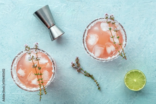 Fototapeta Salty Dog cocktail with fresh grapefruit juice, lime juice, and thyme, overhead flat lay shot with a jigger