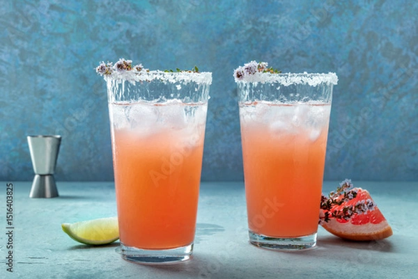 Fototapeta Salty Dog cocktail with fresh grapefruit juice, lime juice, and thyme, side view with a jigger and fresh fruit