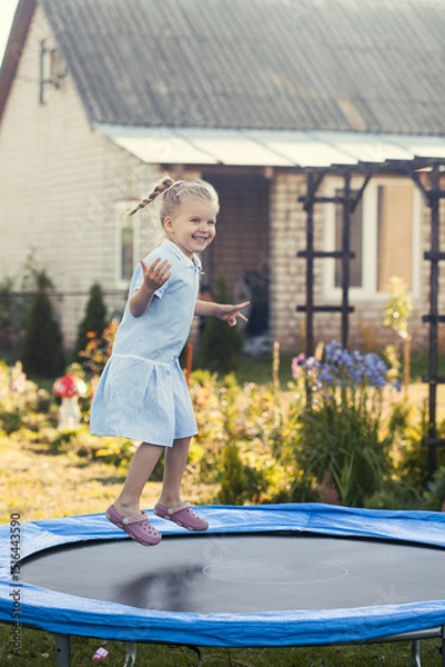 Obraz Little girl jumping on a trampoline on a summer day.