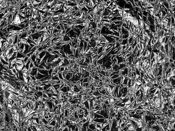 Fototapeta Crinkled metallic foil with a textured pattern of reflective surfaces and sharp creases, creating a visually complex and chaotic arrangement, ideal for abstract or industrial themes