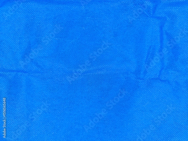 Fototapeta Bright blue textured fabric with subtle wrinkles and a grainy surface pattern, showcasing variations in shading and light. The material appears soft and is evenly distributed