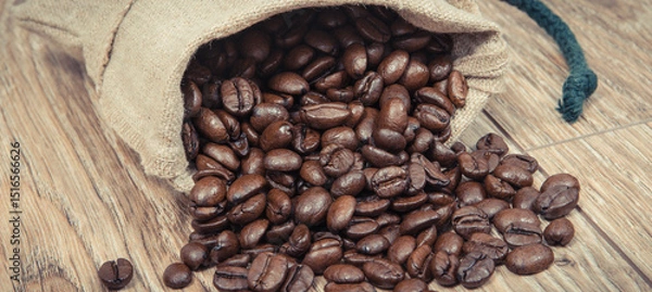 Obraz Heap of dark roasted coffee grains in jute bag