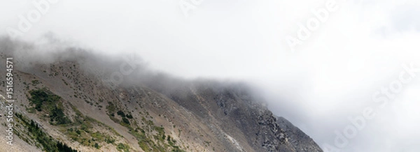 Fototapeta Panorama of mountain scene with scree and mist on top and partly transparent sky
