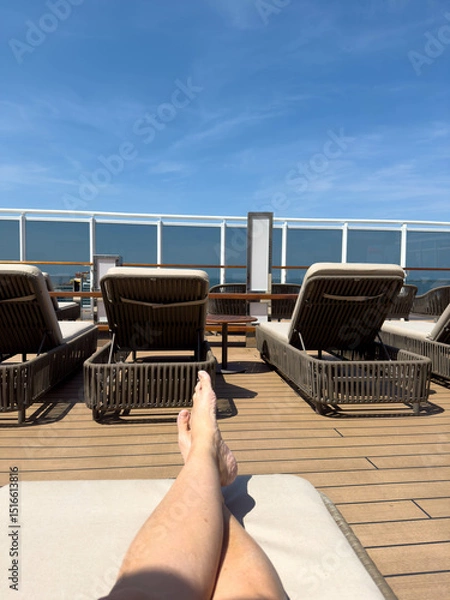 Fototapeta A person on a lounge chair on the a cruise ship overlooking the ocean.