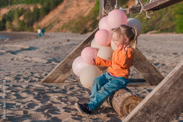 Fototapeta Cute little child runs with balloons by the sea with beautiful scenery