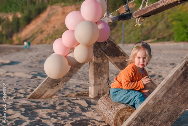 Fototapeta Cute little child runs with balloons by the sea with beautiful scenery
