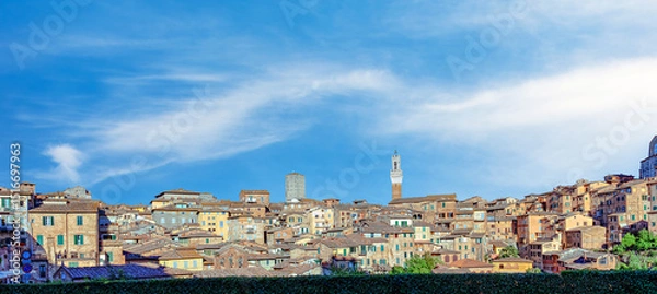Fototapeta View of medieval Siena showcasing charming buildings with terracotta roofs, elegant towers, and a clear blue sky, offering a glimpse of Italian history and architecture.