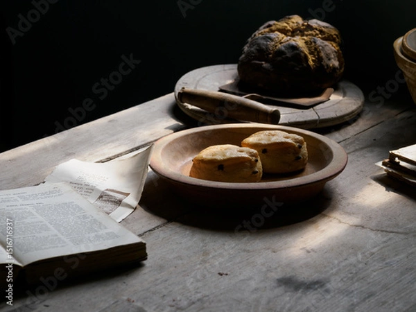 Fototapeta Rustic bread and scones on a wooden table in soft, natural light.