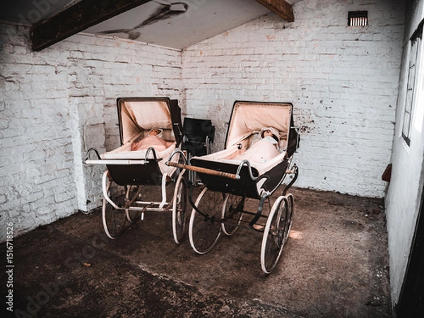 Fototapeta Vintage prams in an old brick-walled garage evoke a nostalgic atmosphere.