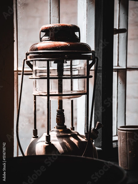 Fototapeta Vintage lantern casting shadows beside a rustic window on a sunny day.
