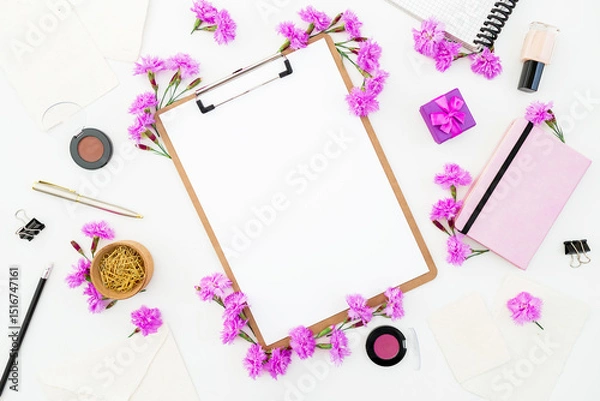 Fototapeta Workspace flat lay with clipboard, purple flowers, notebook, makeup and stationery on white background.