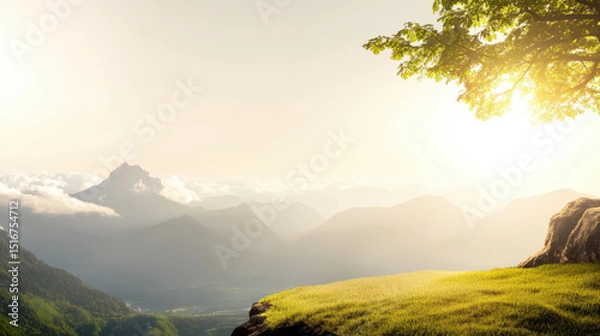 Fototapeta Serene sunrise over fog drenched mountain range, with grassy foreground and tree branch extending into frame, creating peaceful and cinematic atmosphere