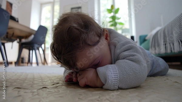 Fototapeta Baby lying on the floor, focused on hands, exploring surroundings, engaged in tactile play, development of fine motor skills, quiet moment of concentration in a home environment