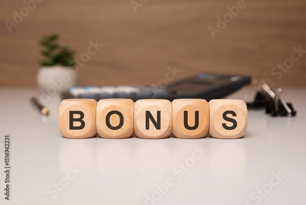 Obraz Wooden blocks spelling BONUS on an office desk with blurred office items in the background
