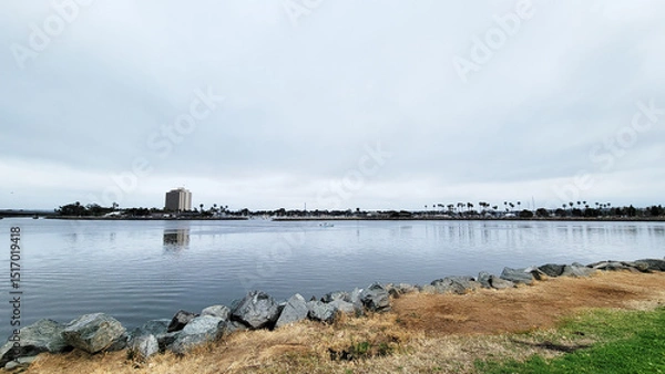 Fototapeta Marina and hotels in Quivira Basin as seen across mirror-like water surface of bay entrance channel from Mission Point Park, San Diego, California