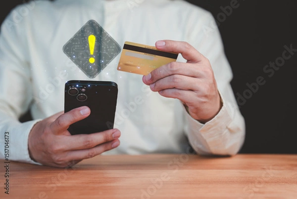 Fototapeta Adult man holding a credit card and mobile phone with a warning sign overlay, symbolizing online scams, fraud, security risks, transfer money and financial caution in digital transactions.