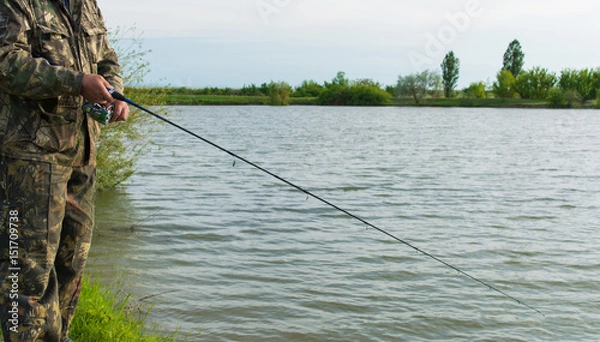 Fototapeta Рыбак со спиннингом на озере.