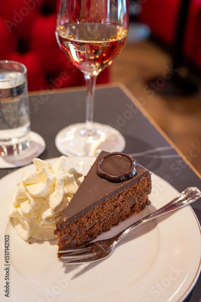 Obraz Piece of famous Sachertorte chocolate cake with apricot jam of Austrian origin served with whipped cream in old classic cafe-restaurant in Vienna