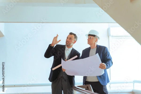 Fototapeta Architect and engineer reviewing blueprints at construction site