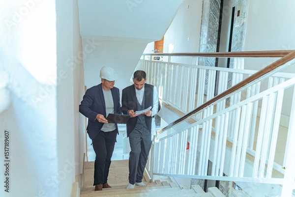Fototapeta Architect and engineer reviewing blueprints at construction site