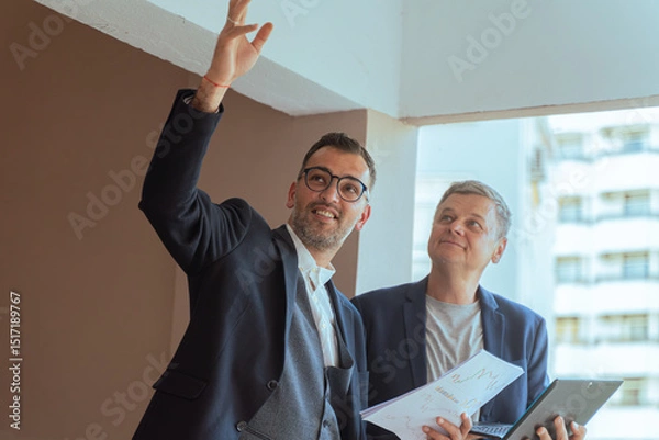 Fototapeta A two man businessman Reviewing Documents and Digital Tablet in Modern Office