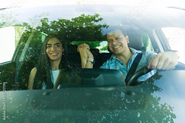 Obraz Happy couple holding hands while driving car