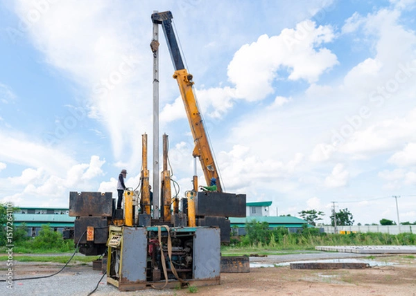 Fototapeta Workers install pile driving by hydraulic static pile driver machine.