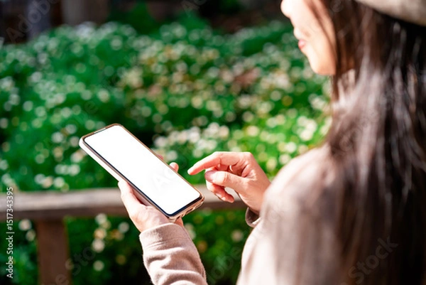 Fototapeta Young female using mobile phone and relaxing in the garden, Modern lifestyle
