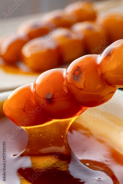 Fototapeta A close-up of traditional Japanese mitarashi dango—skewered rice dumplings grilled to perfection and coated with a glossy, sweet soy sauce glaze. The caramelized surface and rich glaze highlight the a