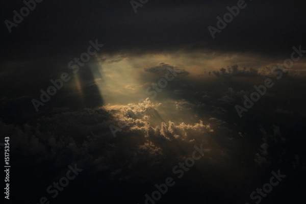 Fototapeta Rays of light shining through dark clouds on another cloud layer for background